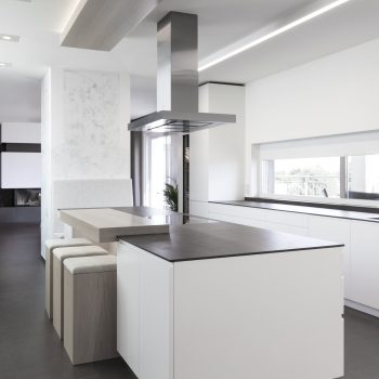 Moderne Kochinsel in weißer Küche mit Holzakzenten in Wien